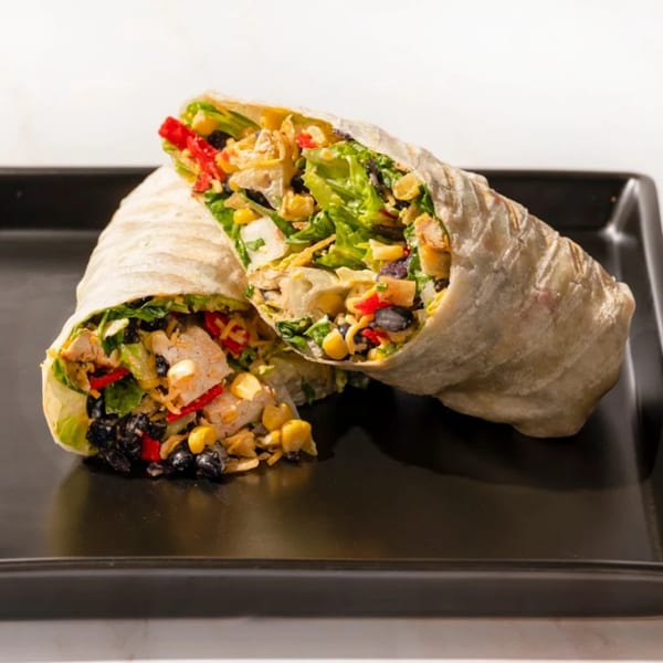 Two halves of a Fresh Millions healthy wrap filled with chicken, corn, black beans, and lettuce.