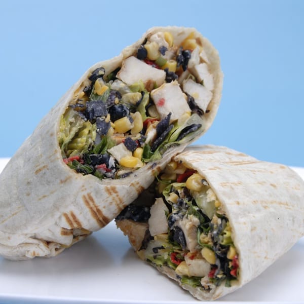 Two Fresh Millions healthy wraps, filled with chicken, corn, black beans, and lettuce, on a white plate.