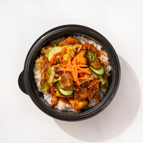 Fresh Millions' healthy bowl with white rice, chicken, zucchini, carrots, broccoli, and cabbage.