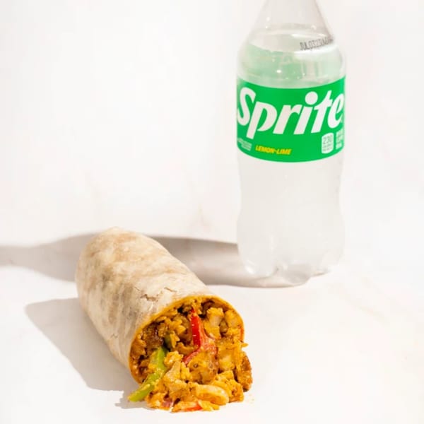 A Fresh Millions burrito, filled with chicken, rice, and vegetables, next to a Sprite bottle.